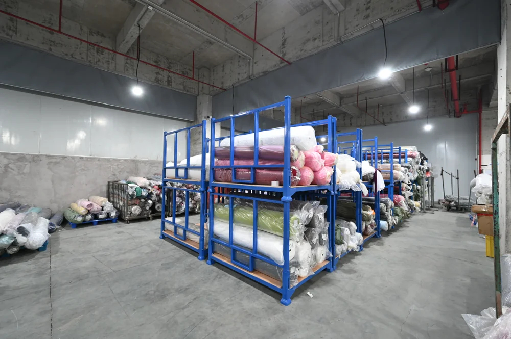 Fabric rolls in multiple colors stored on blue shelving racks in the ASG Fashions fabric warehouse
